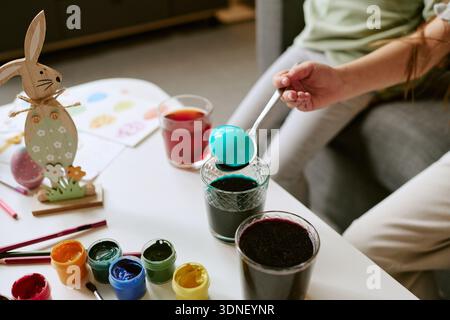 Bambini che colorano l'uovo di Pasqua con vernici durante la preparazione delle vacanze Foto Stock