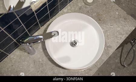 Il moderno lavandino del bagno presenta linee eleganti e finiture eleganti in un ambiente sereno e minimalista Foto Stock