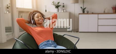 Una giovane donna ama ascoltare musica mentre si rilassa nella sua stanza durante il giorno Foto Stock