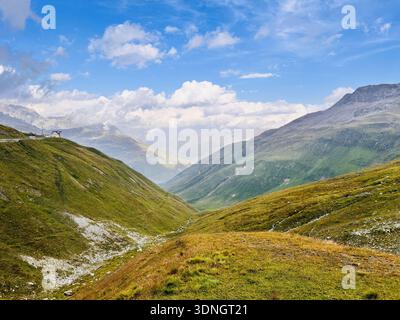 Panoramica della Alpine Valley con Rolling Green Hills e Rugged Mountain Peaks Foto Stock