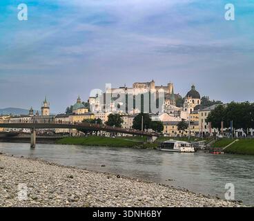 Salisburgo, Austria, 06.10.2025: Vista della città vecchia dalle rive del fiume Salzach, con il ponte Marko Feingold Steg, la cattedrale e il castello nel backgrou Foto Stock