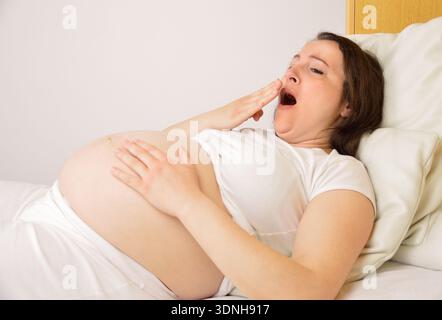 donna incinta che dorme sul suo letto a casa Foto Stock