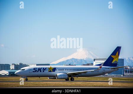 Primo aereo low cost della compagnia aerea giapponese Skymark Airlines (Boeing 737-800) sulla pista dell'aeroporto di Haneda, sotto il cielo azzurro e sullo sfondo del monte Fuji Foto Stock