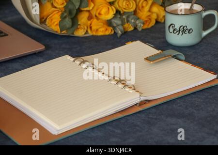 Concetto di pianificazione annuale con notebook a spirale aperta, penna, tazza da caffè su Blue Desk Foto Stock