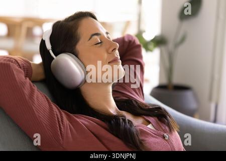 Donna rilassata che ascolta la musica con le cuffie Foto Stock