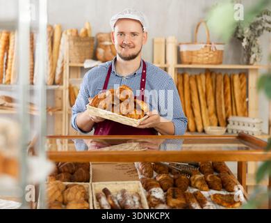 Vendendo croissant freschi in panetteria - il panettiere mette in mostra croissant caldi Foto Stock