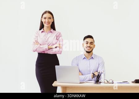 Il team si mette insieme in ufficio moderno durante l'orario di lavoro con laptop e Notes on Desk Foto Stock