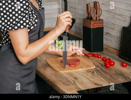 Ragazza con un bel coltello in mano sullo sfondo della cucina. Foto Stock