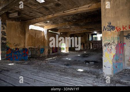 Ampia vista interna della sala abbandonata con graffiti, macerie e pilastri di cemento presso la base dell'aeronautica militare di San Pablo a Siviglia, Spagna. Foto Stock