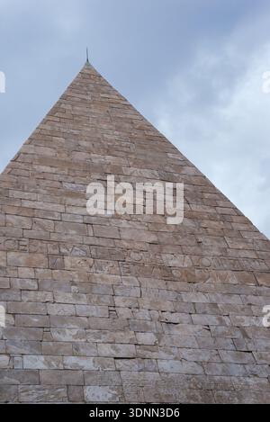 18 gennaio 2026, Roma, Italia: La Piramide di Cestio si erge bruscamente contro un cielo grigio, i suoi antichi blocchi di pietra e l'iscrizione latina visibile sul Foto Stock