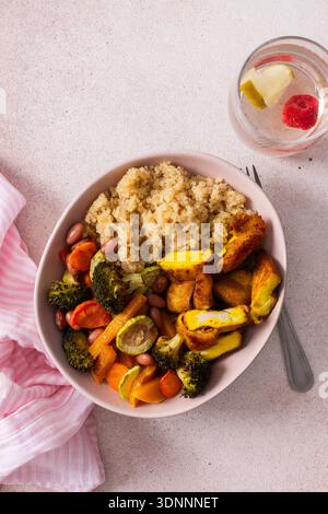 Una nutriente colazione include una ciotola di quinoa accompagnata da vibranti patate dolci al forno, carote, zucchine, fagioli e pollo alla curcuma. abbinato a un'insalata fresca a lato Foto Stock