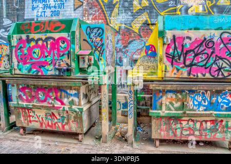 Due cassonetti sono ricoperti di graffiti. C'è la parola "guanto" Foto Stock