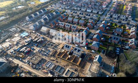 Vista aerea di un progetto di costruzione di abitazioni, che mostra un mix di abitazioni completate e attività di costruzione in corso con vari macchinari a Des Foto Stock