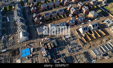 Vista aerea di un cantiere residenziale con case parzialmente costruite, ponteggi, macchinari e materiali sotto un cielo limpido al Desire by Strat Foto Stock