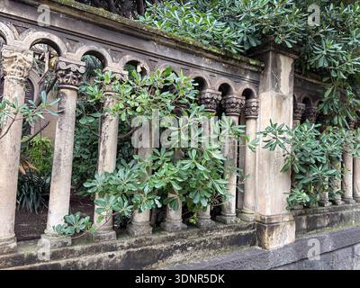 Balaustra con colonne decorative in pietra locale, forse roccia lavica, che circonda il verde lussureggiante di Catania, Sicilia, Italia. Foto Stock