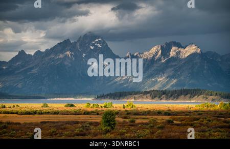 I cieli tempestosi passano sopra la testa mentre il sole sorge sul lago Jackson nella catena montuosa di Teton nel Wyoming. Foto Stock