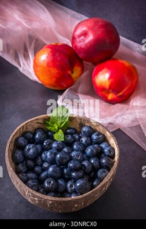Il simbolismo dell'abbondanza è rappresentato dal frutto intero e tagliato: Uva in grappoli, una nettarina aperta che rivela la sua fossa, e un mucchio che scorre liberamente Foto Stock