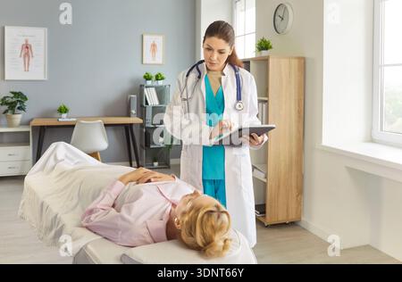 Giovane paziente donna sdraiata sul divano in ospedale e che parla con il medico in clinica medica Foto Stock