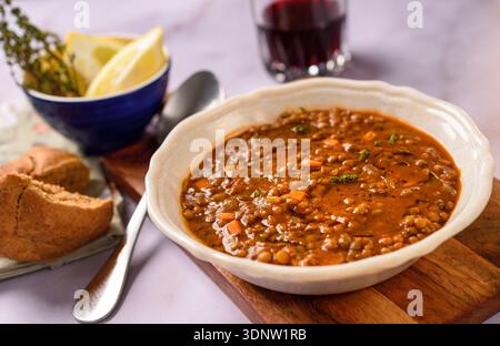 Tradizionale zuppa greca di lenticchie servita in un ristorante rustico con olio d'oliva, erbe aromatiche e stile mediterraneo da tavola. Foto Stock