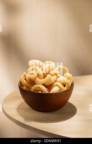 Kap Moo, croccanti croccanti crostate di maiale tailandese servite in una ciotola di legno su un tavolo leggero. Tradizionale spuntino tailandese con consistenza croccante, gusto saporito e minim naturale Foto Stock