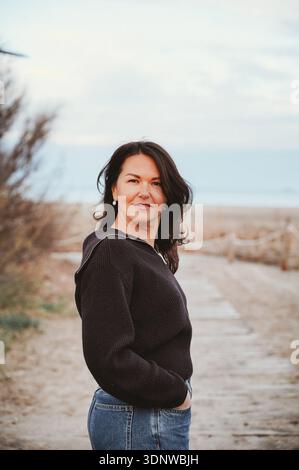 Donna che sorride in spiaggia con outfit casual Foto Stock