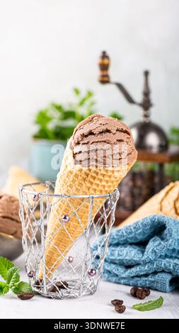 Cono gelato al cioccolato in un cestello decorativo con foglie di menta fresche e chicchi di caffè Foto Stock