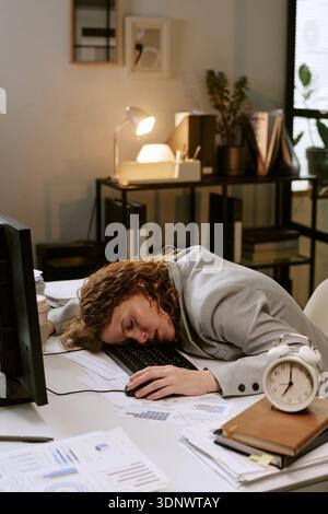 Giovane donna che dorme sulla scrivania durante il Business Workday Foto Stock
