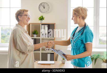 Infermiera donna che consulta pazienti anziani in clinica, stretta di mano calda e amichevole Foto Stock