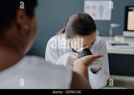 Giovane asiatica dermatologa femminile che esamina braccio di mezza età donna nera Foto Stock
