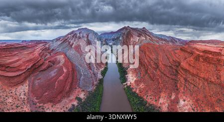 Spettacolare vista aerea dei canyon rossi e stratificati che fiancheggiano il tortuoso Rio San Juan nello Utah, USA, sotto un suggestivo cielo nuvoloso Foto Stock