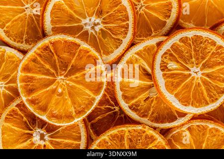 Vista dall'alto delle vivaci fette di arancio delicatamente essiccate, che mostrano texture intricate e ricchi motivi di colore. Ideale per alimenti e ingredienti naturali Foto Stock