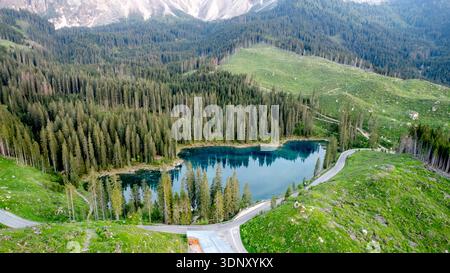 Veduta aerea dello splendido Lago di Carezza, immerso tra foreste sempreverdi e circondato dalle maestose Dolomiti, che mette in mostra la natura incontaminata Foto Stock