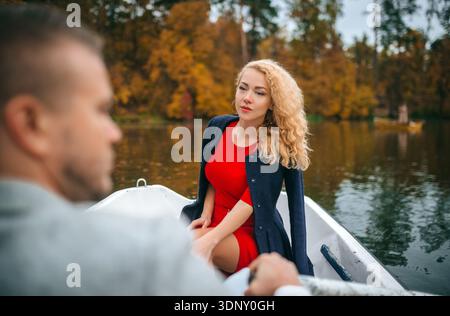 Una coppia amorevole gode di un tranquillo giro in barca su un lago tranquillo, circondato dai colori vivaci di un parco autunnale. La tranquilla scena trasuda romanticismo e Foto Stock