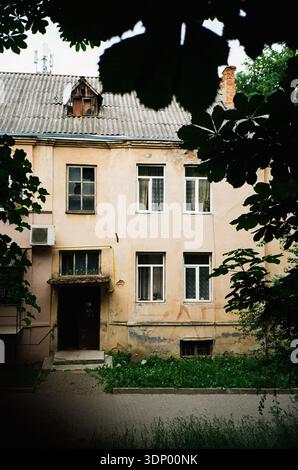 ingresso ad una vecchia casa gialla a due piani con castagni in primo piano e un prato su pellicola da 35mm Foto Stock