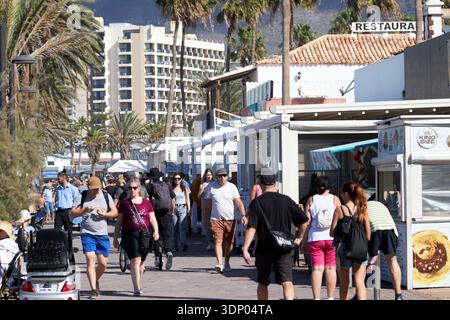 i turisti camminano lungo il lungomare pedonale playa de las americas tenerife isole canarie spagna nel sole di gennaio d'inverno Foto Stock