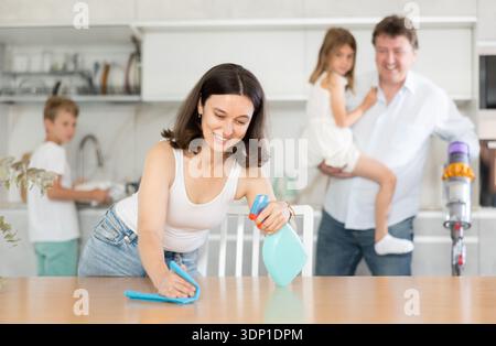 Famiglia felice con due bambini che fanno la pulizia in cucina Foto Stock