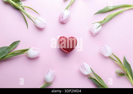 Tulipani e confezione regalo su sfondo rosa piatto, romantico modello di carta Foto Stock