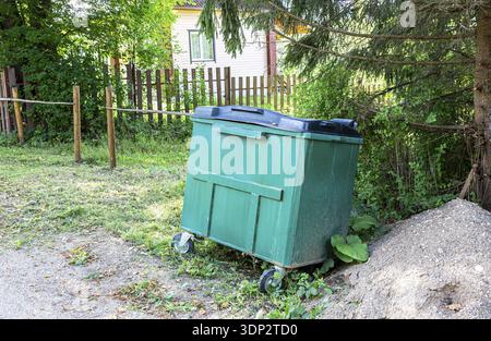 Contenitore verde di rifiuti in plastica all'aperto in giornata di sole Foto Stock