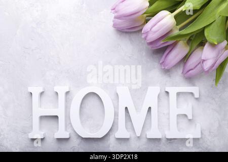 Legno decorativo lettere che compongono la parola Casa con tulipani rosa sulla pietra grigia sullo sfondo Foto Stock