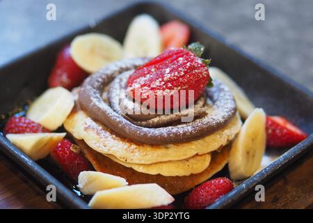 Deliziosa pila di pancake con frutta e cioccolato Foto Stock