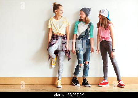 Moda, conversazione e gruppo di adolescenti a muro per legare, amicizia o ridere insieme. Felice, chiacchierata e ragazze che escono con figo Foto Stock