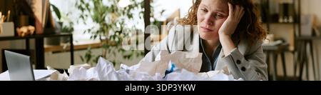 Giovane donna che vive Burnout mentre affronta pile di documenti Foto Stock