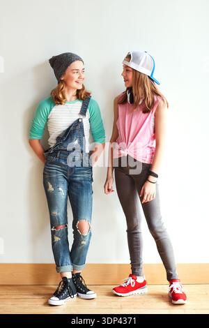 Moda, conversazione e adolescenti a muro per legarsi, amici migliori o ridere insieme. Felici, chiacchierate e ragazze che escono con cool, trendy o. Foto Stock