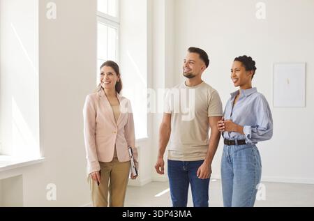 Agente immobiliare, agente immobiliare che presenta alle giovani coppie uno spazio interno moderno, consulenza professionale Foto Stock
