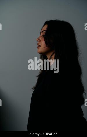 Profilo Ritratto di Una donna con vista laterale con illuminazione Moody Studio e abbigliamento nero Foto Stock
