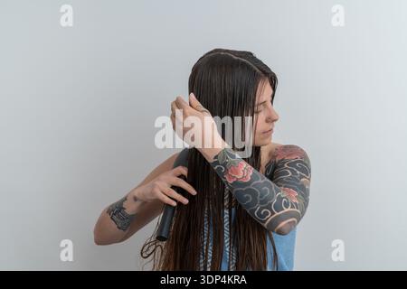 Donna che pulisce lunghi capelli bagnati durante la routine di bellezza mattutina Foto Stock