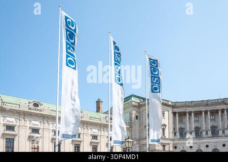 Bandiere bianche dell'OSCE che sventolano di fronte allo storico complesso Hofburg a Vienna durante il tempo limpido Foto Stock