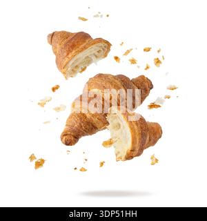 Croissant e briciole al burro appena sfornato che cadono isolati su sfondo bianco. Interi e rotti in mezzo croissant. Pasticceria o barba Foto Stock