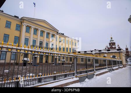 Stadtblick Helsinki, 12.02.2026 Das Finnische Präsidentenpalais Presidentinlinna a Helsinki mit klassizistischer Fassade und finnischer Staatsflagge auf dem Dach. Im Vordergrund das schmiedeeiserne Tor mit vergoldeten Spitzen. Rechts im Hintergrund ist die Uspenski-Kathedrale zu sehen. Winterliche Szene mit Schnee während einer Kältewelle. Helsinki Uusimaa Finnland *** Vista città Helsinki, 12 02 2026 il Palazzo Presidenziale finlandese Presidentinlinna di Helsinki con facciata neoclassica e bandiera nazionale finlandese sul tetto in primo piano il cancello in ferro battuto con punte dorate Uspenski Foto Stock