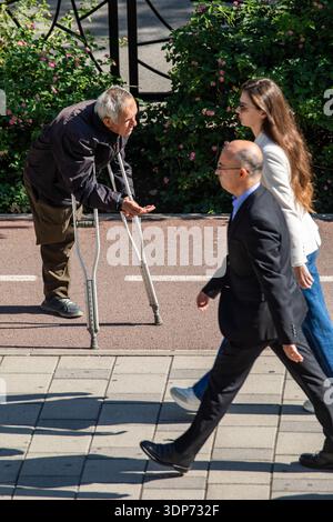 Persone che passano mendicanti a una gamba di fronte alla Moschea di Namazgah a Tirana, Albania Foto Stock